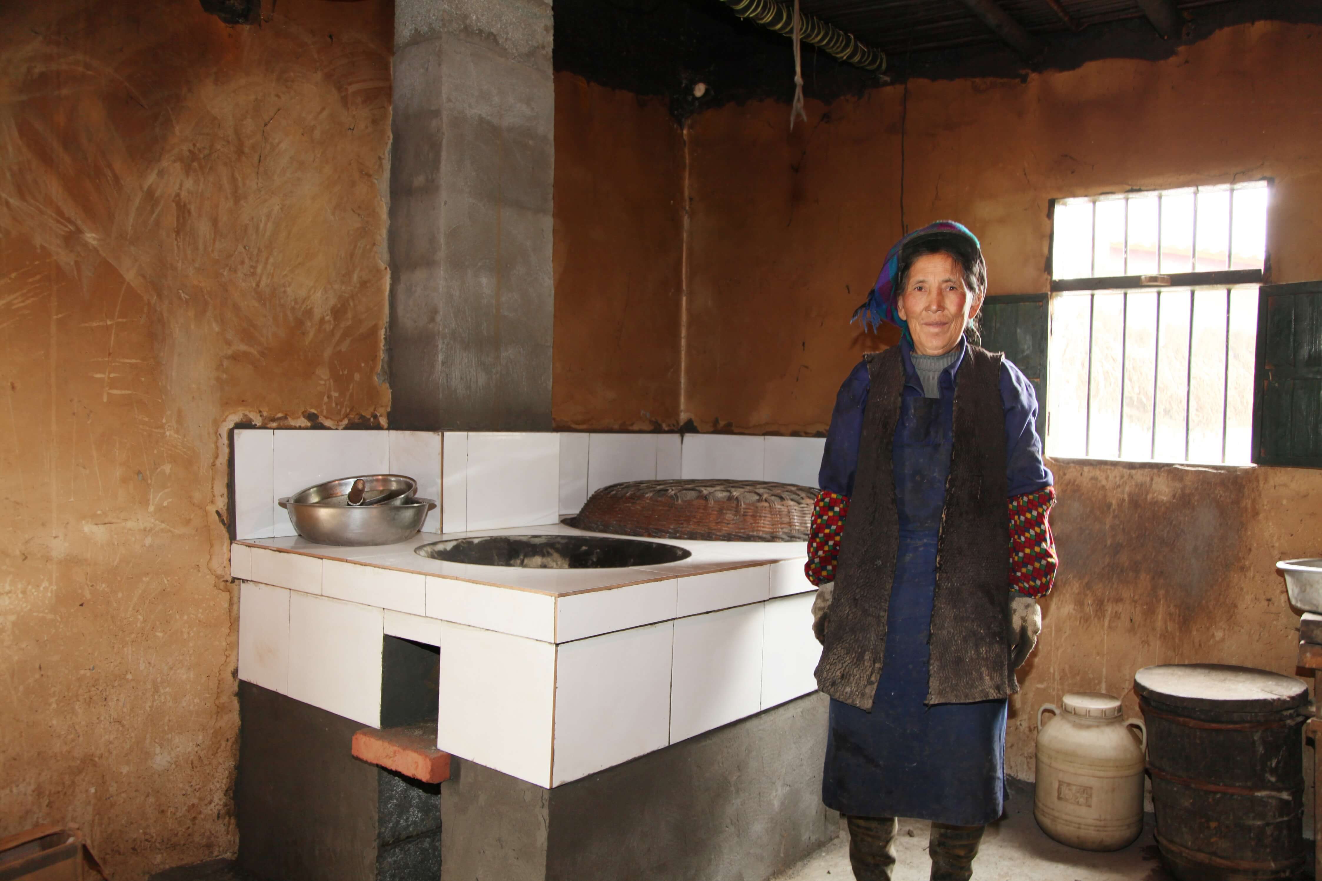 House owner standing next to the new firewood-saving cookstove.