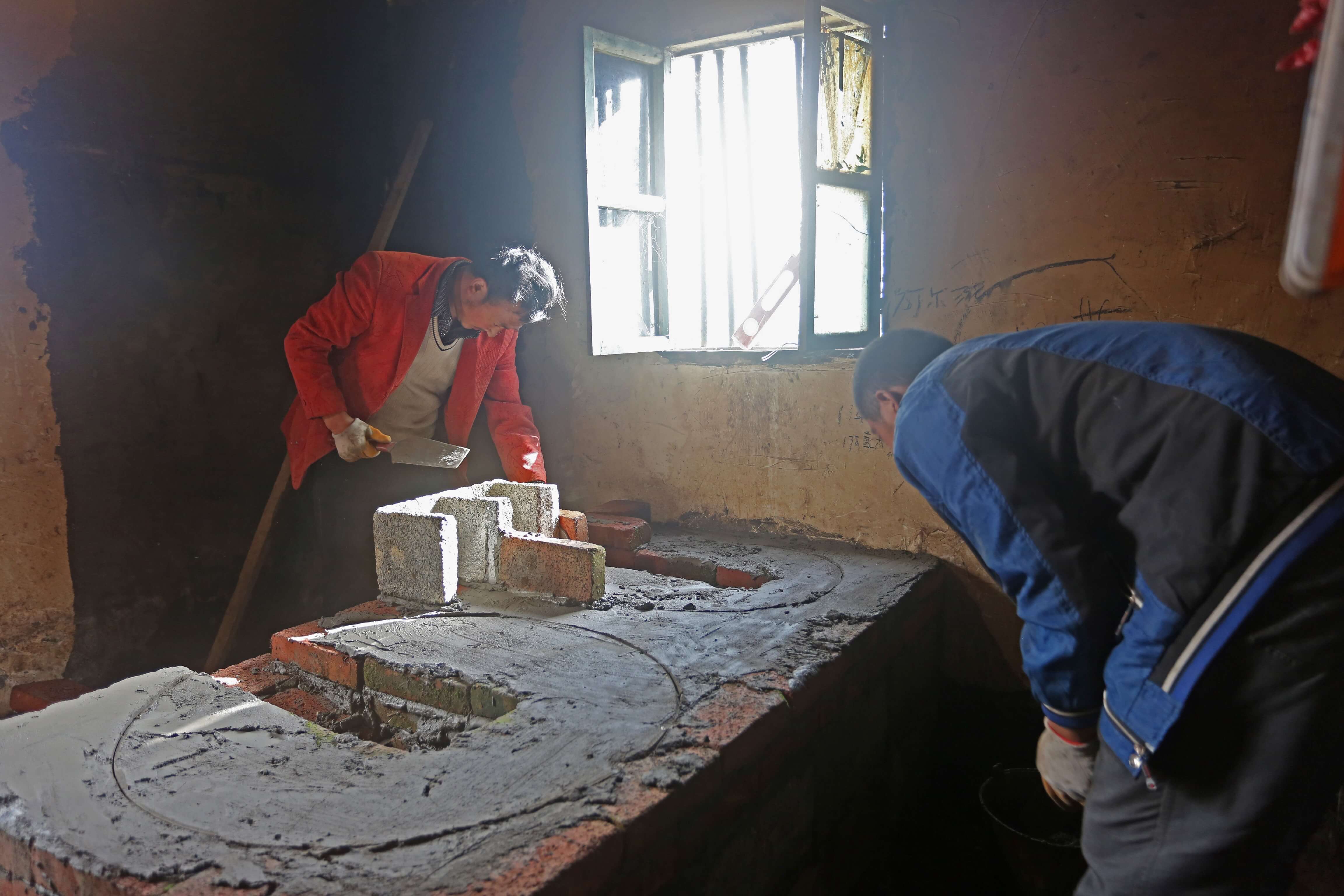 Workers constructing the firewood-saving stove for a household. 