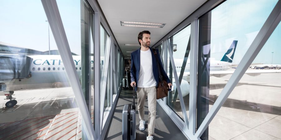 A passenger walking through the boarding bridge after disembarking a Cathay Pacific aircraft.