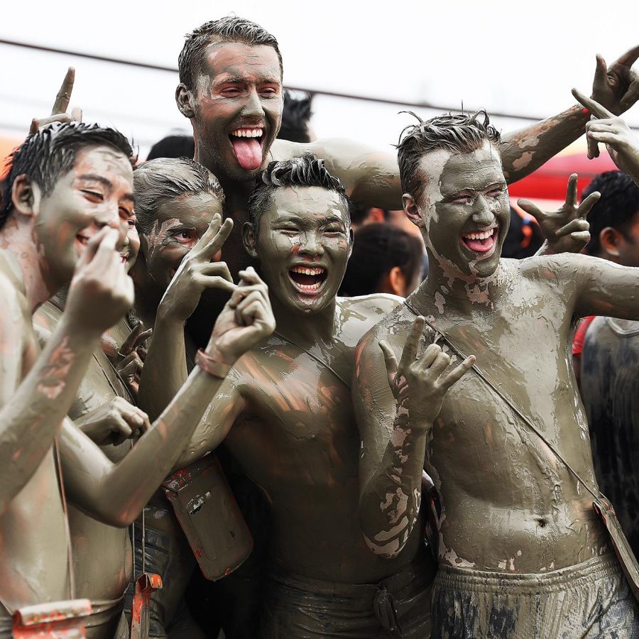 Five men covered in mud while smiling