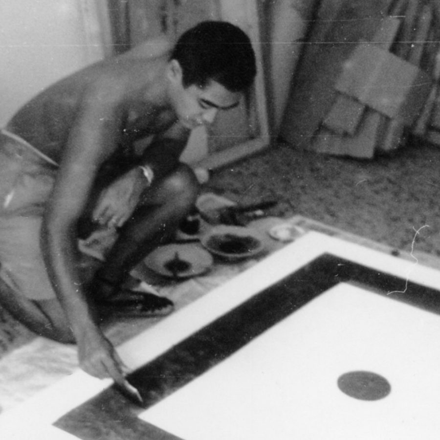 Black and white photo of artist painting on the floor