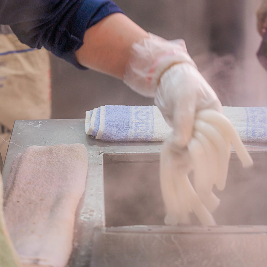 A set of hands handling noodles over a sink