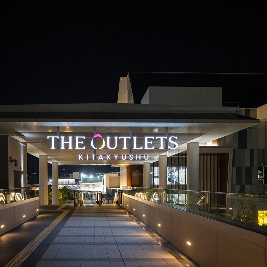 An exterior view of the escalator and entrance to The Outlets Kitakyushu at night