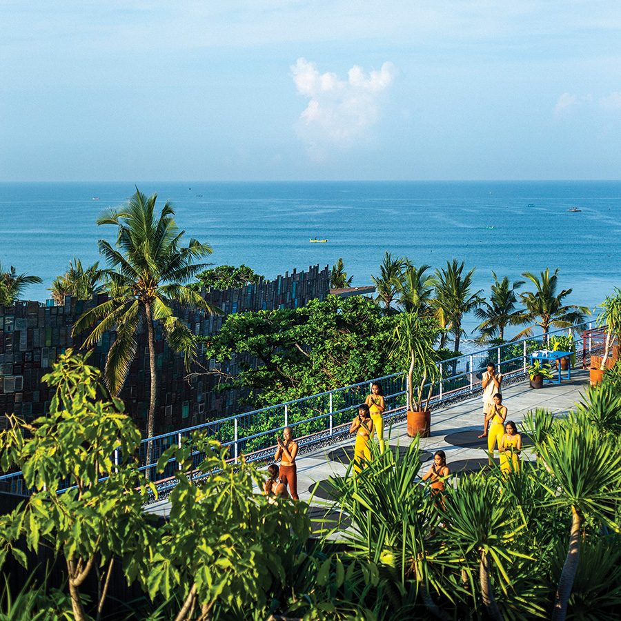 A shot of people in front of trees and the ocean