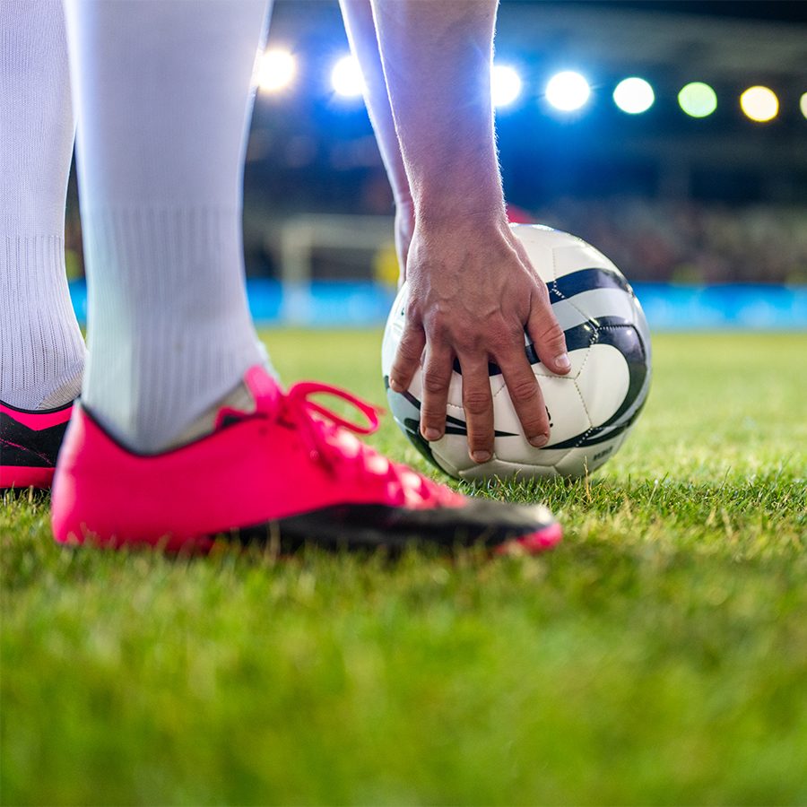 Crop of football boots and hand holding football