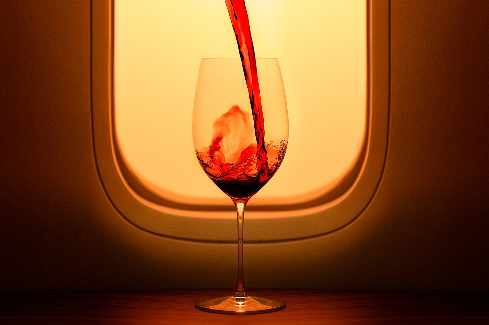 A glass of wine in front of an airplane window