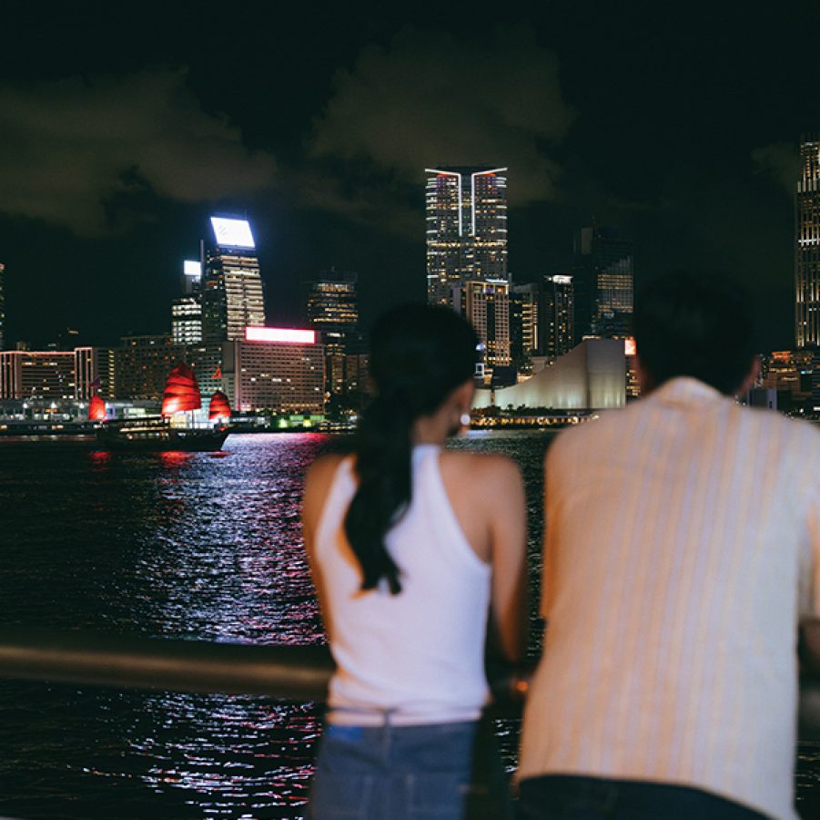 A couple, man and woman, on a date at night looking out to Victoria Harbour