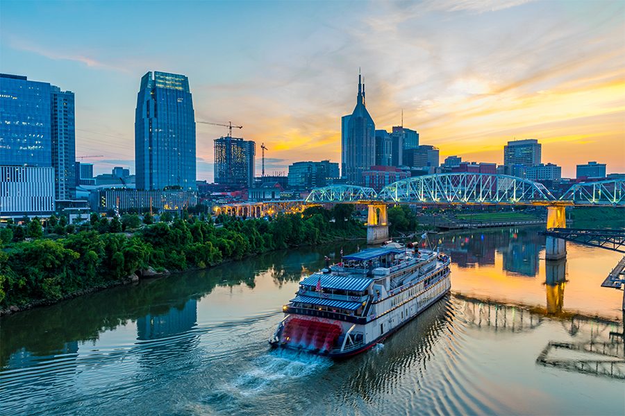 Boat sailing through a river in Nashville with a view of the skyline behind.