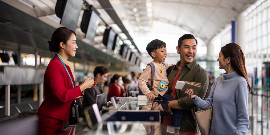 A Cathay Pacific airport staff assisting a family at the check-in counter.