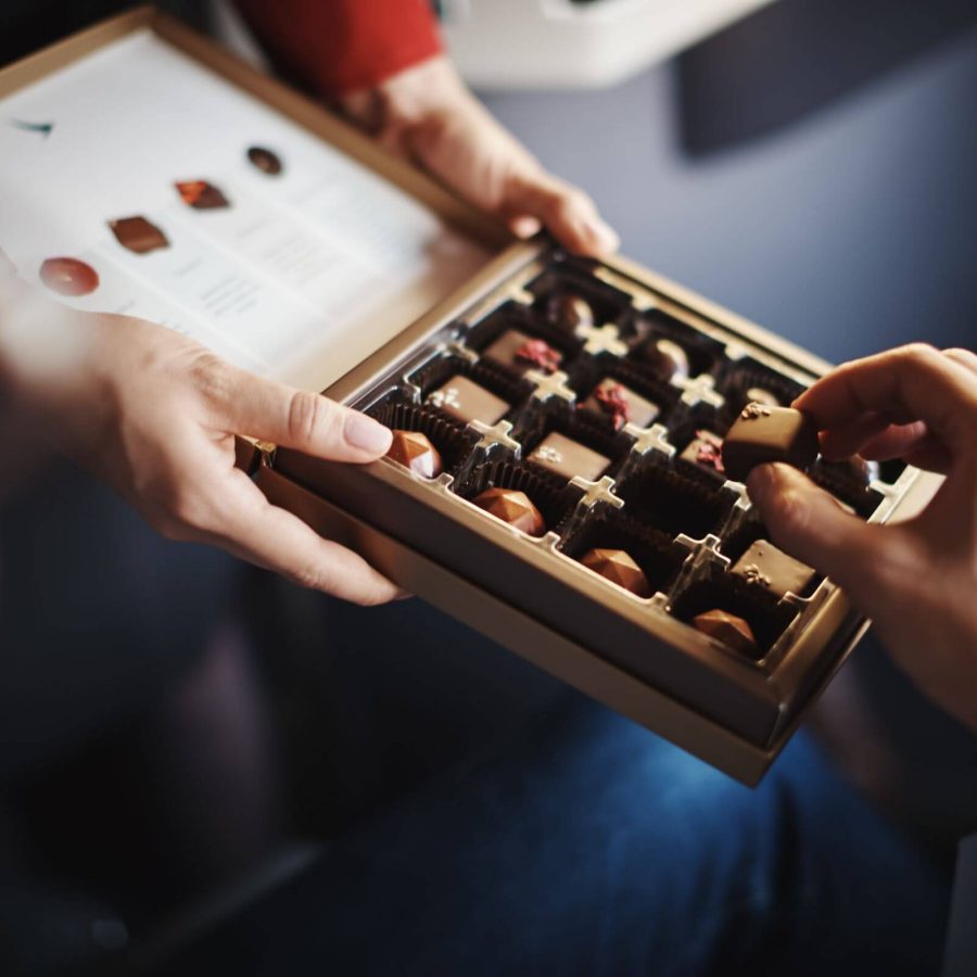 A Cathay Pacific flight attendant holds a box of chocolates for a passenger to choose.