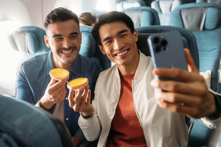 Two men taking selfie while holding egg tarts