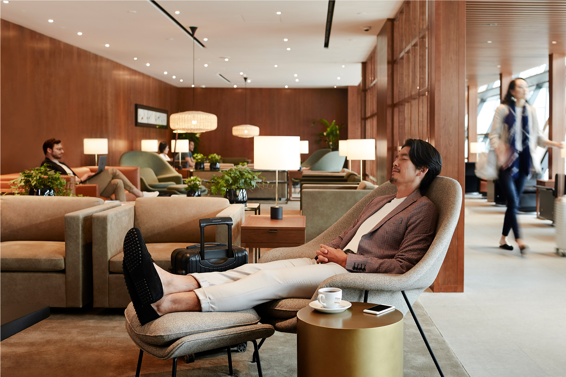 A male passenger is relaxing in a lounging chair inside the Cathay Pacific Lounge at Shanghai Pudong International Airport.