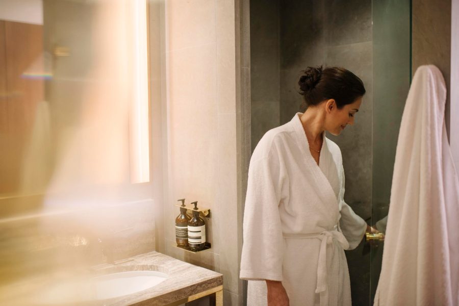 A caucasian woman in a spa robe inside a private shower at a Cathay Pacific lounge.