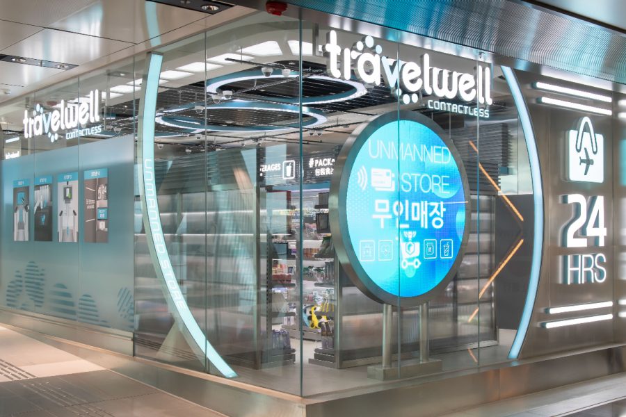 The shopfront of travelwel at Hong Kong International Airport, with a large blue circular sign shown behind transparent glass.