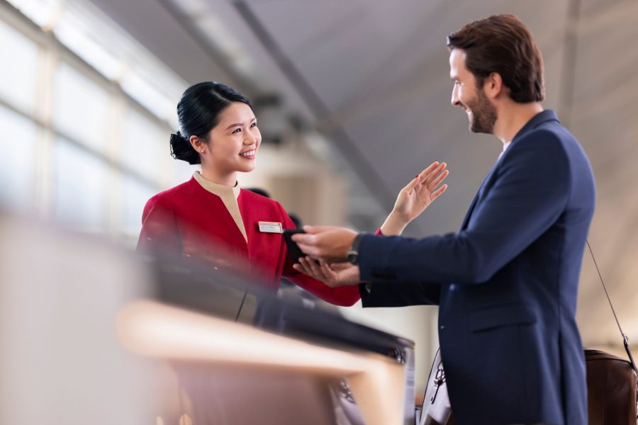 A Cathay Pacific ground crew member handling a passenger enquiry. The two are smiling at each other. 